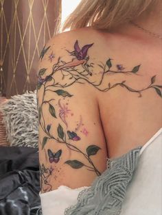 a woman's shoulder with flowers and butterflies on her left arm, next to a bed