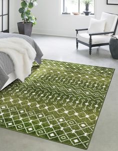 a bedroom with a green rug on the floor and a white chair next to it