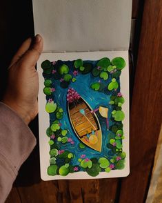 someone is holding up a card with a boat in the water and lily pads on it