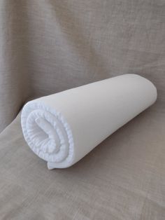 a rolled up white blanket on top of a bed