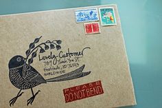 an envelope with some stamps on it and a bird in the middle, sitting on a table