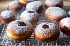 powdered sugar covered donuts on a cooling rack with cherries in the middle