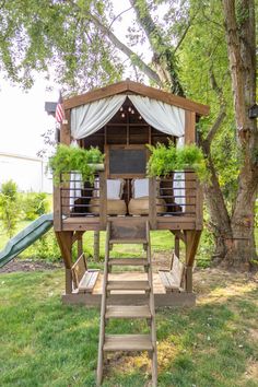 a small wooden structure with plants on top and stairs leading up to it in the grass