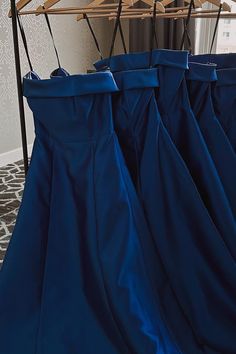 three blue pants hanging on a rack in a room