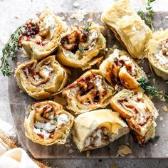 several rolls with meat and cheese are on a cutting board