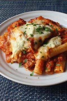 a white plate topped with pasta covered in sauce and parsley on top of it