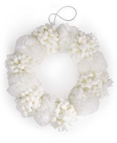 a white wreath with pom - poms hanging from the side on a string