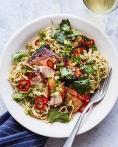 a white bowl filled with noodles, meat and veggies