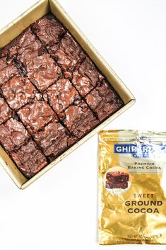 a box of brownies next to a bag of ground cocoa on a white surface