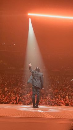 a man in a suit walking across a stage with his hand up to the sky