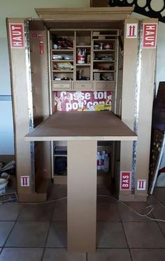 the inside of a cardboard storage unit with boxes on top and shelves above it that are labeled in red