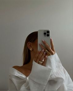 a woman taking a selfie with her phone in front of her face and wearing gold rings