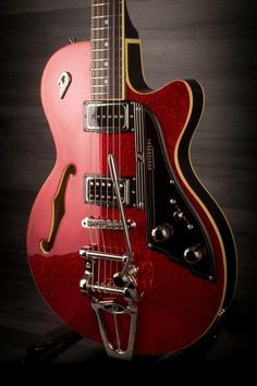 a red electric guitar sitting on top of a wooden table