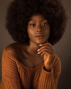 a woman with an afro is posing for the camera and looking off to the side