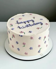 a white cake with purple flowers and the words happy birthday written on it