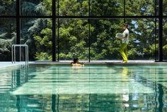 a man standing next to a swimming pool in front of a window with trees outside