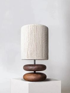 a table lamp sitting on top of a white block with a wooden base and fabric shade