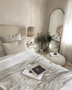 a bed with white linens and pillows in a bedroom next to a large mirror