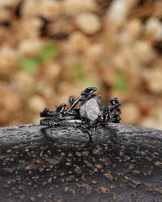 a diamond ring sitting on top of a black piece of metal in front of some rocks