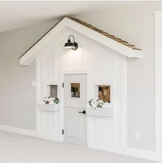 a white dog house with flowers in the windows