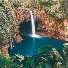 there is a large waterfall in the middle of this body of water that is surrounded by greenery