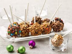 there are many candy balls on the plate and one is filled with chocolate, sprinkles, and other candies