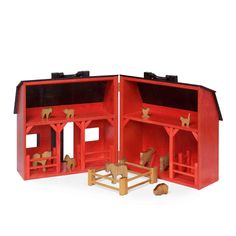 a red wooden toy house with horses inside