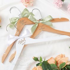 three wooden hangers with personalized names on them and flowers in the foreground