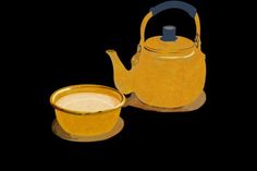 a yellow tea kettle and cup on a black background