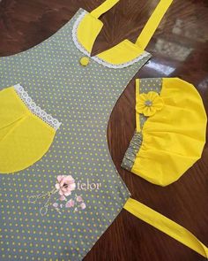 a yellow and gray apron with flowers on the front, two matching bibs are sitting next to each other