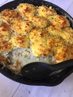 a casserole dish with chicken and cheese in it on a white wooden table