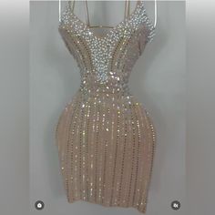 a dress hanging up on a rack in front of a white wall with silver beads