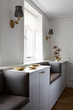 a white room with two gray benches next to each other and a lamp on the wall