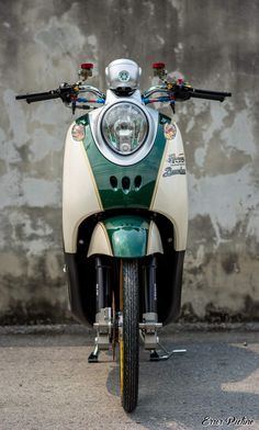 a green and white scooter parked in front of a wall