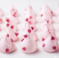 there are many small pieces of pink frosting with red hearts on them and one piece has been cut in half