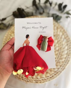 a person holding up a card with a red dress on it