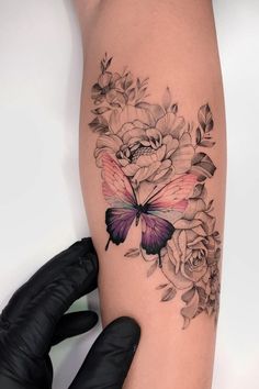 a woman's arm with flowers and a butterfly on it, while she is wearing gloves