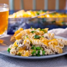 a white plate topped with macaroni and cheese next to a glass of beer