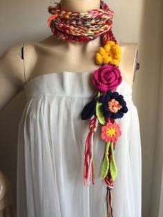 a woman wearing a white top and multi colored crocheted scarf on her neck