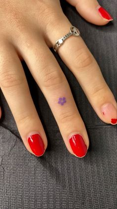 a woman's hand with red nail polish and a ring on her left finger