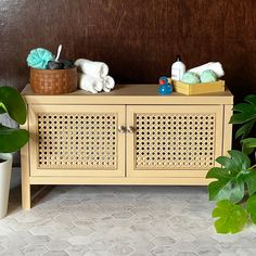 a wooden cabinet with two baskets on top of it and some plants in front of it