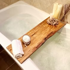 a bathtub with soap and candles in the tub, next to it is a wooden cutting board