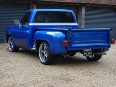 a blue pick up truck parked in front of a garage