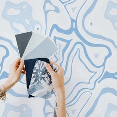 a person holding up a piece of paper in front of a blue and white wall