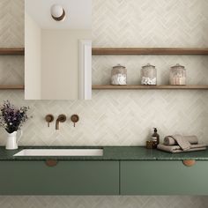 a bathroom with green counter tops and wooden shelves on the wall next to it is a white vase filled with flowers