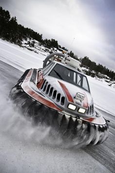 a car driving on snow covered ground with trees in the backgrouds behind it