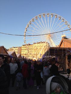 a crowd of people standing around a ferris wheel