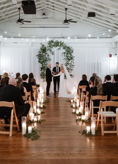 a bride and groom standing at the end of their wedding ceremony with candles in front of them