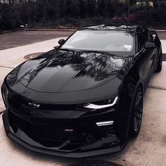 a black chevrolet camaro parked in front of a house