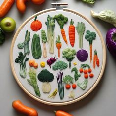 an embroidery project with vegetables and fruits on the table next to each other, including carrots, broccoli, onions, cabbage, celery, and more